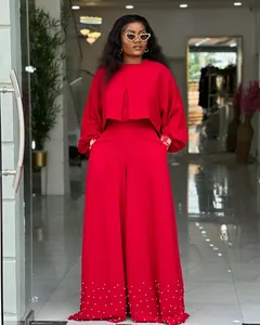 Elegant red two-piece set with lantern sleeve top and pearl-studded wide-leg trousers.