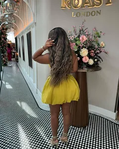 Stylish yellow bubble hem mini dress with backless design in a chic lounge setting.
