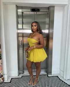 Model wearing a vibrant yellow halter backless bubble mini dress in a stylish interior