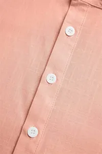 Close-up of cotton linen fabric and white buttons on a peach stand collar shirt
