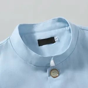 Detailed macro view of mandarin collar and button on light blue cotton linen jacket