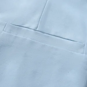 Close-up detail of light blue cotton-linen suit jacket with welt pocket texture.