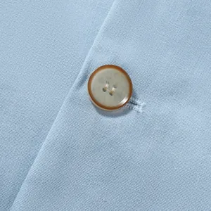 Macro detail of button and woven texture on light blue cotton linen suit jacket