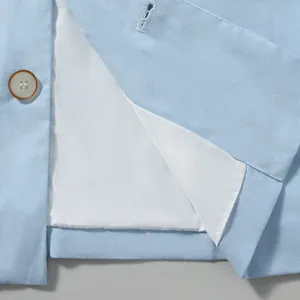 Close-up detail of light blue cotton linen suit jacket with white lining and button