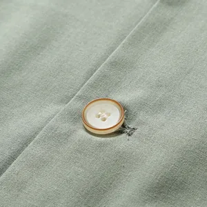Close-up detail of a button and the cotton linen texture of a men's suit jacket.