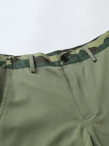 Detail shot of men's olive green cargo shorts with camouflage waistband and button.