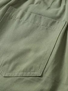 Macro view showing the durable stitching and twill fabric of an olive green cargo pocket