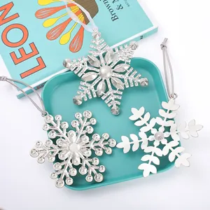 Dettaglio di tre decorazioni uniche a forma di fiocco di neve in metallo argento per Natale
