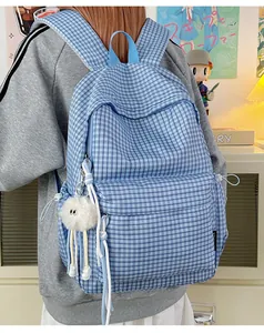 Detailansicht eines hellblauen karierten Rucksacks mit süßem weißen Plüschanhänger