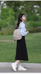 Junge Frau trägt einen leichten rosa Nylon-Rucksack in einer sonnigen Parkumgebung
