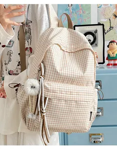 Detailansicht eines beigen Rucksacks mit Karomuster und einem süßen flauschigen Anhänger