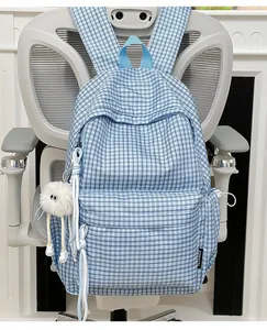 Detaillierte Nahaufnahme des hellblauen karierten Schülerrucksacks mit süßem flauschigen Anhänger