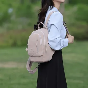 Zaino monospalla leggero in nylon beige da donna in un ambiente casual all'aperto