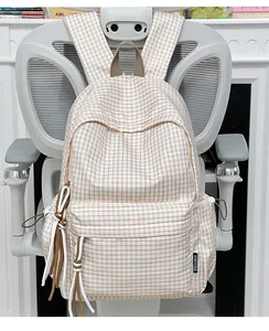 Nahaufnahme eines karierten Rucksacks mit dekorativen Quasten und Markenetikett.