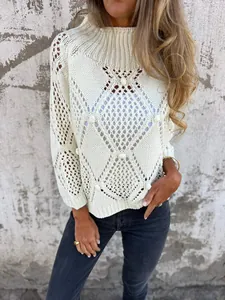 Détail d'un pull en maille ajourée crème avec des motifs évidés et de petits pompons