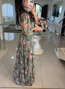 Side view of an elegant sage green tiered maxi dress featuring a vibrant pink leaf print.