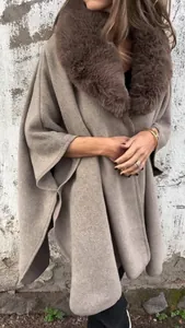 Close-up detail of an elegant taupe wool poncho featuring a plush faux fur collar for winter