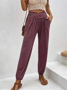 Detail view of women's high-waisted purple jogger pants with cross-waist design and pockets.