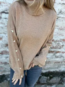 Nahaufnahme eines legeren Rollkragen-Strickpullovers mit dekorativen Knopfärmeln in Tan