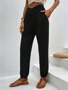 Detail of high-waisted crossover black lounge pants with loose fit and cuffed ankles