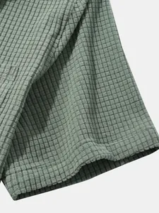 Macro detail shot showing the premium soft waffle texture of the sage green corduroy shirt.