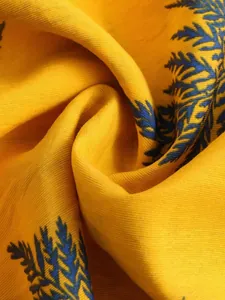 Macro detail of yellow summer beach shirt fabric showing blue leaf print and texture