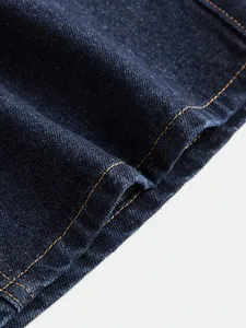 High-quality macro detail of dark blue denim fabric texture with orange contrast stitching
