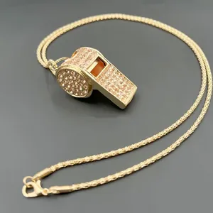 Primo piano dettagliato di una collana con ciondolo a fischietto oro e strass