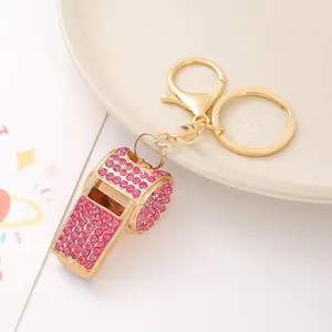 Dettaglio di un portachiavi dorato con un fischietto decorato con strass rosa acceso