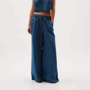 Detail showing wide-leg denim trousers with drawstring waist in vintage washed finish.