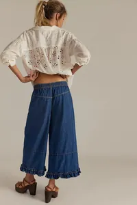 Back view of women's wide-leg cropped denim pants featuring a stylish ruffle hem.