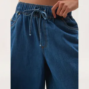 Detailed close-up of vintage washed blue denim pants with drawstring elastic waist.