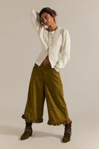Casual olive green wide-leg cropped jeans with feminine ruffle hem on a female model