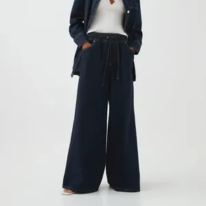 Detail showing the dark blue wide-leg denim pants with drawstring waist and deep pockets.