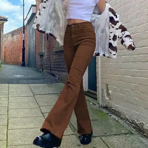 Model wearing high-waisted brown flared jeans in a stylish outdoor brick street setting.