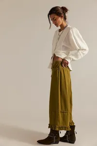 Detailed view of women's olive green wide-leg cropped jeans with stylish ruffled hemline
