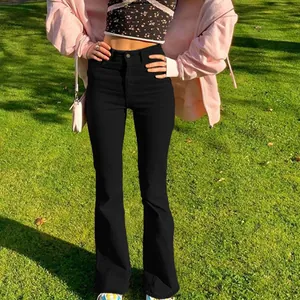 Fashionable slim fit flared black denim pants styled in a sunny outdoor park setting