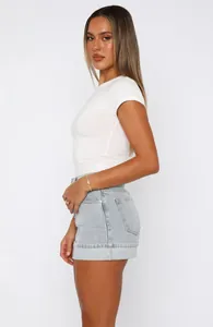 Πλάγια όψη λευκού T-shirt και ανοιχτόχρωμης τζιν φούστας με γυρισμένο στρίφωμα