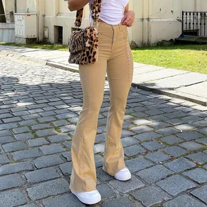 Close-up of women's khaki slim flare jeans paired with leopard print bag on street