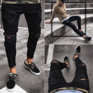 Detailed view of men's black ripped skinny jeans featuring stretch fabric and ankle zippers