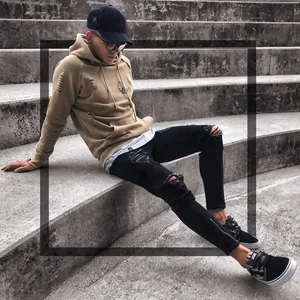 Detailed view of men's black ripped skinny jeans with ankle zippers and distressed texture