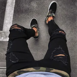 Detail view of men's black ripped skinny jeans with functional ankle zipper closure