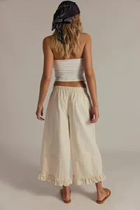 Back view of cream women's wide-leg cropped jeans with elegant ruffled hem detail