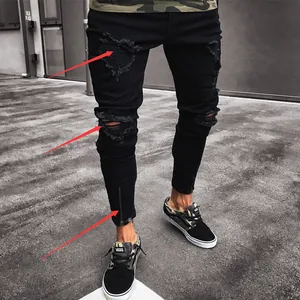 Close-up of black ripped skinny jeans with distressed details and ankle zippers.