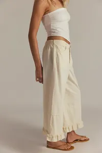 Side view of a woman wearing cream wide-leg cropped jeans with ruffled hem detail