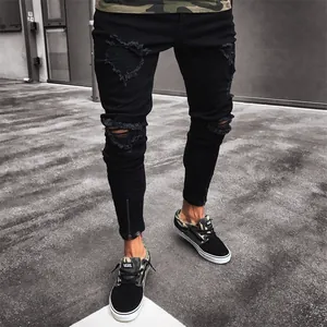 Detail of men's black ripped skinny jeans featuring ankle zippers and distressed knees