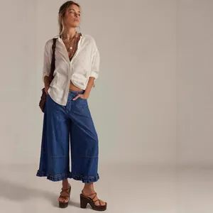 Fashionable women's wide-leg cropped denim jeans featuring an elegant ruffled hem detail