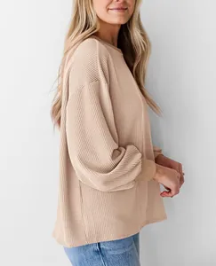 Zijaanzicht detail van een losse beige geribbelde sweatshirt met lange mouwen