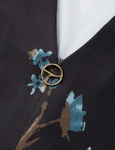 Detailed macro view of V-neckline with decorative gold metal ring on floral print tunic
