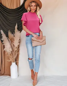 Elegant pink ruffled short sleeve blouse styled with blue jeans and a chic beige hat.